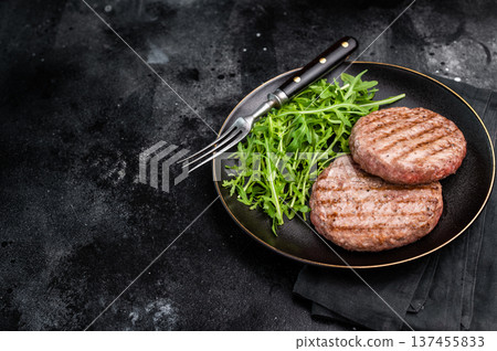 Grilled beef and pork meat patty paired with fresh veggies, an essential component for gourmet burgers. black background. top view Grilled beef and pork meat patty paired with fresh veggies, an essential component for gourmet burgers. black background. top view 137455833