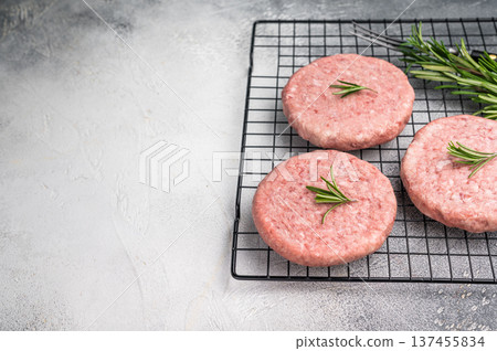 Close up of a juicy raw meat patty cutlet, ideal for crafting mouthwatering sandwiches and savory dishes. white background. top view Close up of a juicy raw meat patty cutlet, ideal for crafting mouthwatering sandwiches and savory dishes. white background. top view 137455834