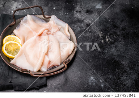 Fresh raw squid ready for preparation, perfect for sushi, stir-fries, or gourmet seafood dishes. black background. top view Fresh raw squid ready for preparation, perfect for sushi, stir-fries, or gourmet seafood dishes. black background. top view 137455841