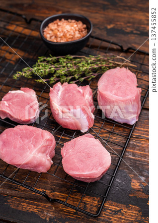 Uncooked pork loin medallion, cut tenderloin ready to be seasoned and cooked into a delicious gourmet dish. wooden background. top view Uncooked pork loin medallion, cut tenderloin ready to be seasoned and cooked into a delicious gourmet dish. wooden background. top view 137455852