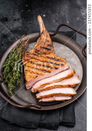Flavorful grilled pork loin chop with bone, expertly cooked to perfection, making it the star of any meal. black background. top view Flavorful grilled pork loin chop with bone, expertly cooked to perfection, making it the star of any meal. black background. top view 137455853