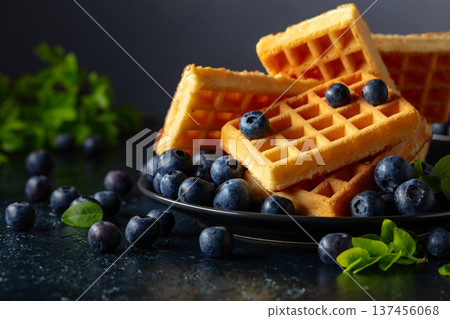 Belgian waffles with fresh blueberries on a black plate. Belgian waffles with fresh blueberries on a black plate. 137456068