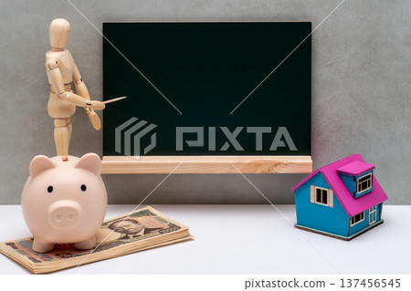 A drawing doll pointing at a blackboard, a house model, a piggy bank, and a 10,000 yen bill 137456545