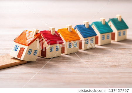 A row of wooden houses one falls as a symbol of the housing crisis. Space for text. 137457797