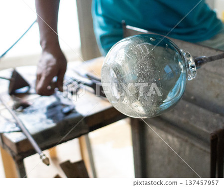 Glassblowing in a glass workshop, creating round glass 137457957