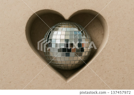 A silver disco ball lies inside a heart shape made of stone. 137457972
