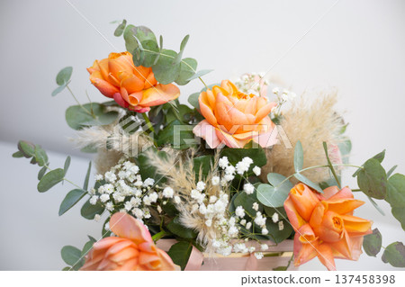 Elegant bouquet of orange roses with eucalyptus leaves placed in a decorative gift box on a white background. Celebration, appreciation, romance, floristry craft, and thoughtful present for special Elegant bouquet of orange roses with eucalyptus leaves placed in a decorative gift box on a white background. Celebration, appreciation, romance, floristry craft, and thoughtful present for special 137458398