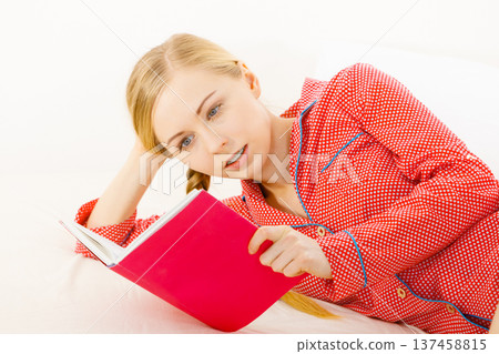 Woman relaxing in bed reading book 137458815