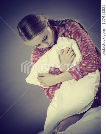 Sad depressed girl in bed gripping pillow Sad depressed girl in bed gripping pillow 137458825