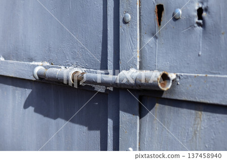 A lock sits firmly on a gate, ensuring security and control over who can enter. The setting highlights a manmade structure in an urban environment 137458940