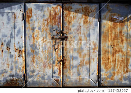 An old metal gate stands in daylight, featuring rust and wear from years of exposure to the elements An old metal gate stands in daylight, featuring rust and wear from years of exposure to the elements 137458967