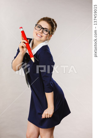 Smiling woman holds big pencil in hand Smiling woman holds big pencil in hand 137459015