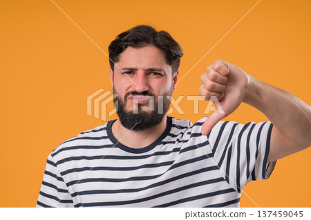 Portrait of unhappy man condemns with sign of dislike. Young millennial guy Portrait of unhappy man condemns with sign of dislike. Young millennial guy 137459045