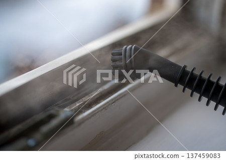 Cleaning the window. Steam device removes dirt from the plastic window frame. 137459083