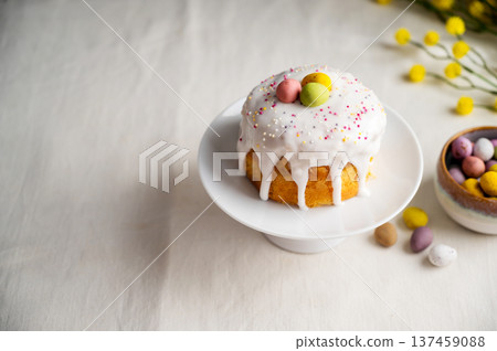 Easter festive cake with icing, sprinkles and eggs candy. White eggs and spring, yellow flower twigs. Easter festive cake with icing, sprinkles and eggs candy. White eggs and spring, yellow flower twigs. 137459088