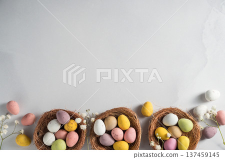 Easter holiday Spring background with mini eggs candy in nests over bright background, copy space Easter holiday Spring background with mini eggs candy in nests over bright background, copy space 137459145