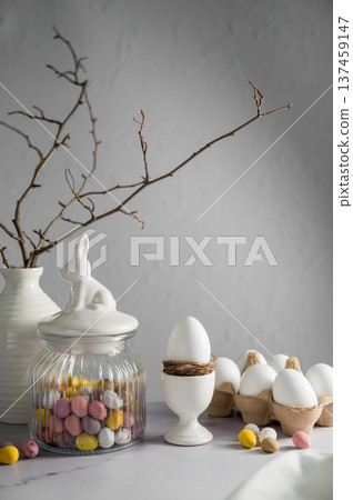 Easter background, table with spring decorations: eggs, candies, twigs in a vase and egg candies. Easter background, table with spring decorations: eggs, candies, twigs in a vase and egg candies. 137459147