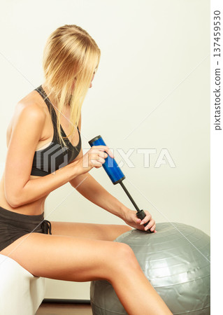 Fitness woman with air pump inflating fit ball Fitness woman with air pump inflating fit ball 137459530