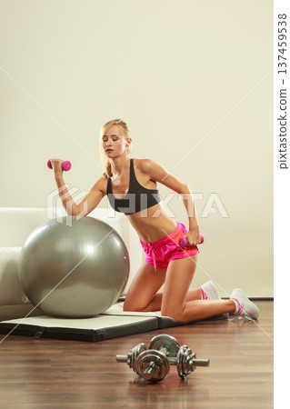 Woman with gym ball and dumbbell doing exercise Woman with gym ball and dumbbell doing exercise 137459538