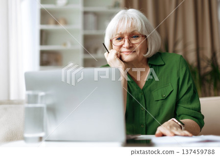 Senior woman looking at laptop screen with thoughtful expression at home Senior woman looking at laptop screen with thoughtful expression at home 137459788