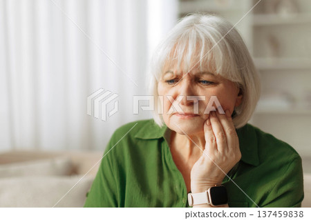 Toothache. Senior woman touching cheek with painful expression while sitting at home 137459838