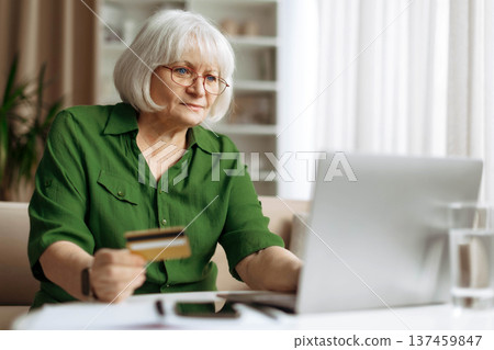 Senior woman making online payment with credit card on laptop at home 137459847