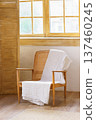 Wooden armchair with woven back and white blanket near window in cozy boho interior 137460245