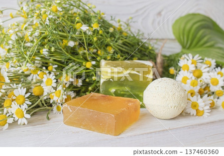 Natural handmade soap with chamomile and bath bomb. Natural handmade soap and chamomile flowers on a white wooden background. Natural handmade soap with chamomile and bath bomb. Natural handmade soap and chamomile flowers on a white wooden background. 137460360