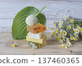 Natural handmade soap with chamomile and bath bomb. Natural handmade soap and chamomile flowers on a white wooden background. 137460365