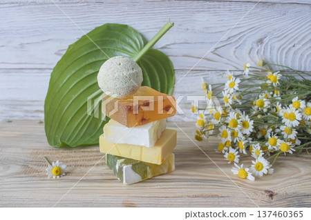 Natural handmade soap with chamomile and bath bomb. Natural handmade soap and chamomile flowers on a white wooden background. 137460365