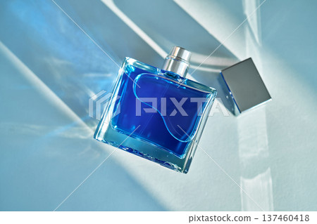 Blue perfume bottle on light background with shadows 137460418