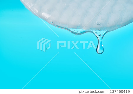 Cotton pad absorbing cosmetic serum drop on blue background 137460419