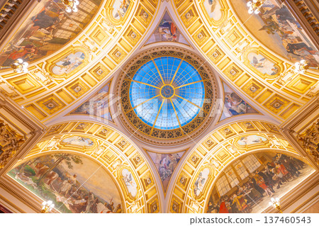 Visitors view the ornamental ceiling with a circular roof window in the Pantheon section of the National Museum of Prague. The design features various artistic elements and lighting. 137460543