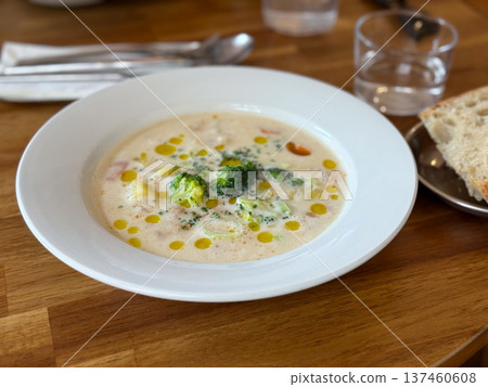 Creamy broccoli soup served in white plate on wooden cafe table. Comfort food, healthy lunch concept and modern restaurant dining presentation. Creamy broccoli soup served in white plate on wooden cafe table. Comfort food, healthy lunch concept and modern restaurant dining presentation. 137460608