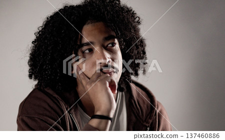 Pensive young african-american man with curly hair looking away and thinking Pensive young african-american man with curly hair looking away and thinking 137460886