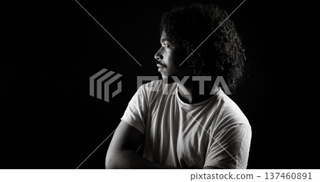 Young african-american man with curly hair looking away on black background Young african-american man with curly hair looking away on black background 137460891