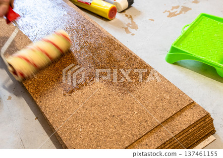 roller applies glue to surface of cork tile 137461155