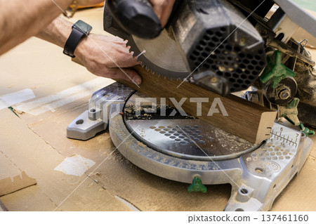 worker trims baseboard with portable circular saw 137461160