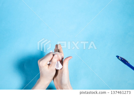 top view of hands crumpling ball on blue top view of hands crumpling ball on blue 137461273