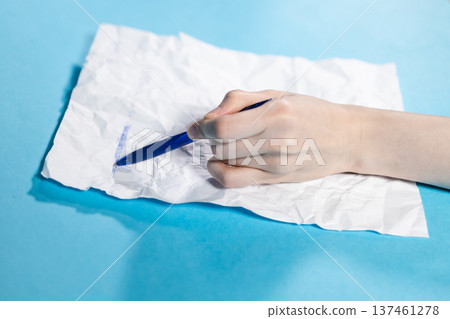 hand with pen crosses out on crumpled paper 137461278