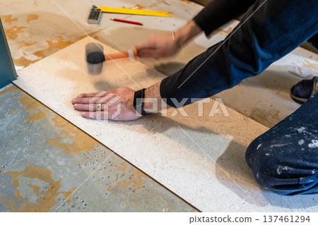 worker glues cork flooring with plastic hammer 137461294