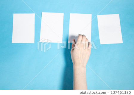 hand chooses from four blank white papers on blue hand chooses from four blank white papers on blue 137461380