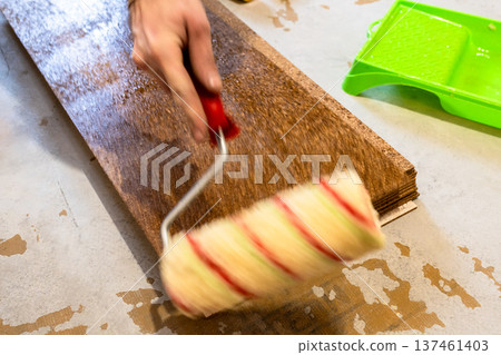 worker applies glue on cork tile with roller worker applies glue on cork tile with roller 137461403
