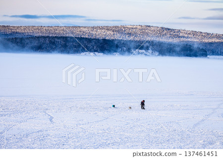 fisherman on frozen sea shore at cold winter day 137461451