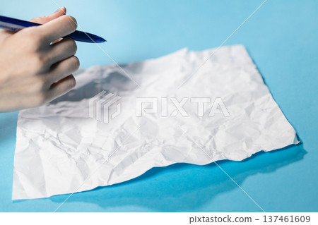 hand with pen over crumpled sheet of paper 137461609