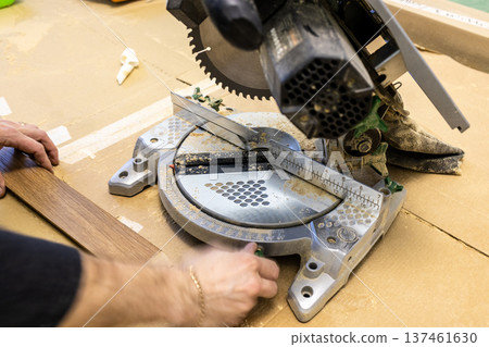 worker marks baseboard near portable circular saw 137461630