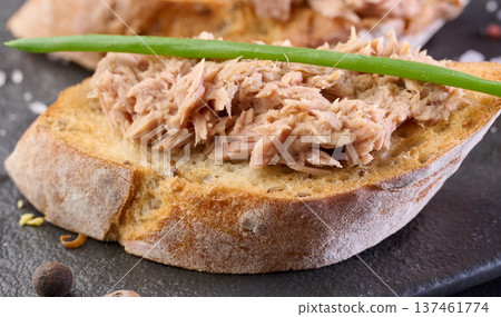 Crispy toasted bread with shredded pink tuna garnished with green onions on a black board Crispy toasted bread with shredded pink tuna garnished with green onions on a black board 137461774