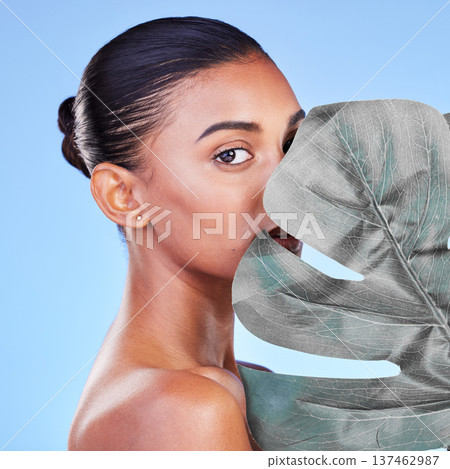 Leaf, skincare and portrait of woman in studio for eco friendly, wellness or cosmetics on blue background. Monstera, face and Indian female with natural dermatology, beauty or organic body care Leaf, skincare and portrait of woman in studio for eco friendly, wellness or cosmetics on blue background. Monstera, face and Indian female with natural dermatology, beauty or organic body care 137462987