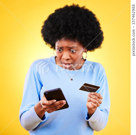Surprised, credit card and woman with phone scam and shock from problem and tech in studio. Stress, mobile and confused from phishing, hacking and ecommerce spam with anxiety and yellow background 137462988