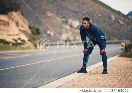 Tired runner man, mountain and rest with earphones, music and thinking for fitness, health and wellness in street. Guy, outdoor and training for marathon with fatigue, vision and burnout in nature 137463032